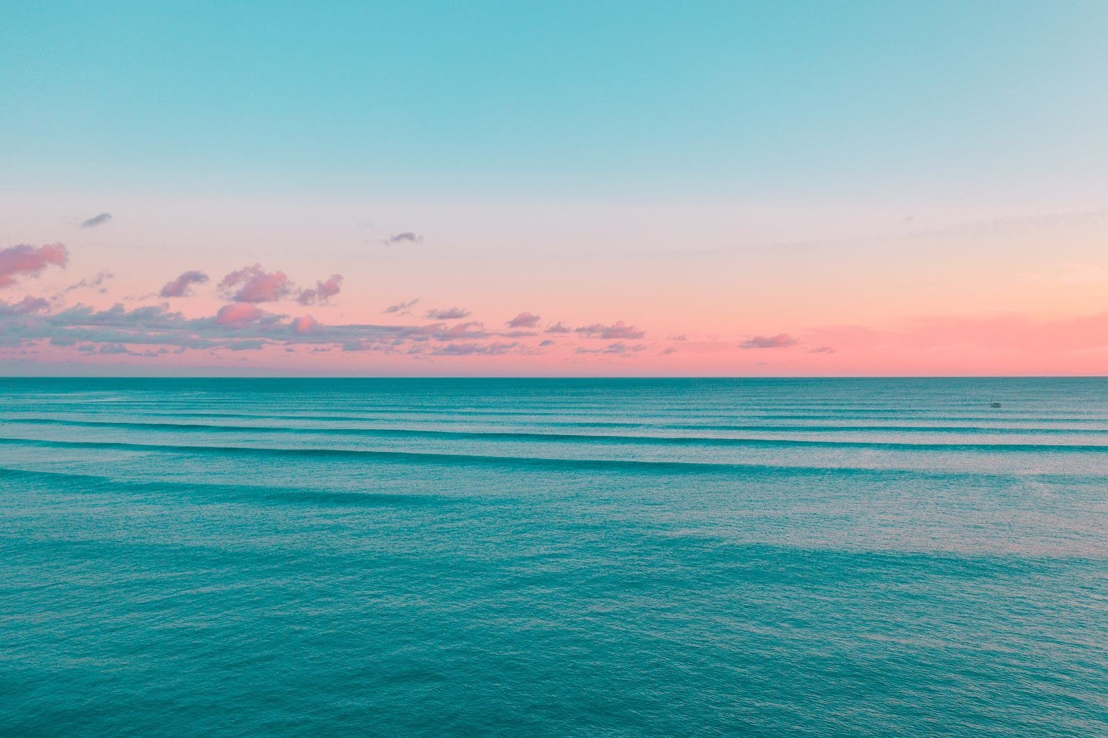 The sun rising over a calm ocean, gold light spreading across the water.