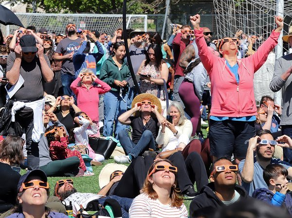 Crowd wearing eclipse glasses looking up at the sky during a solar eclipse