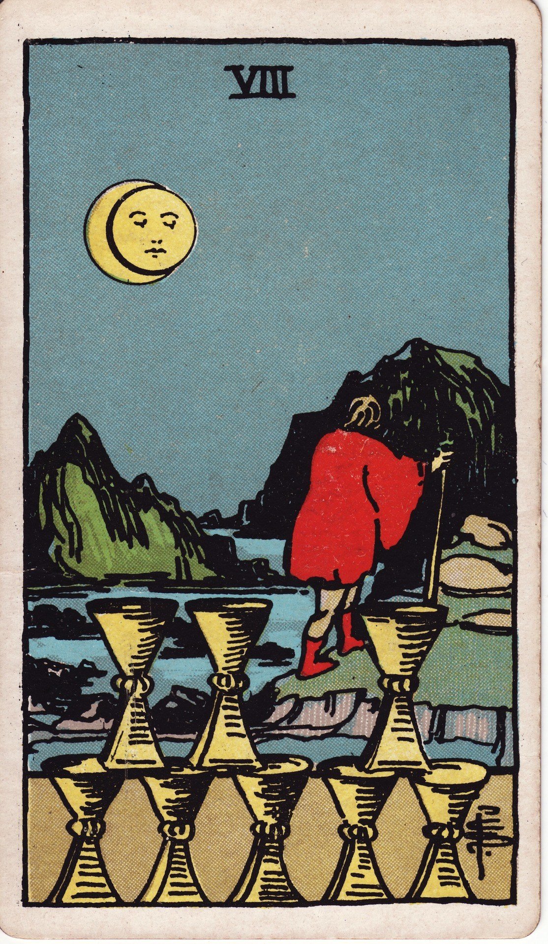 The Eight of Cups from the Rider-Waite-Smith tarot deck: a cloaked figure with a staff walks away from eight stacked golden cups under a moonlit sky, heading toward distant mountains.