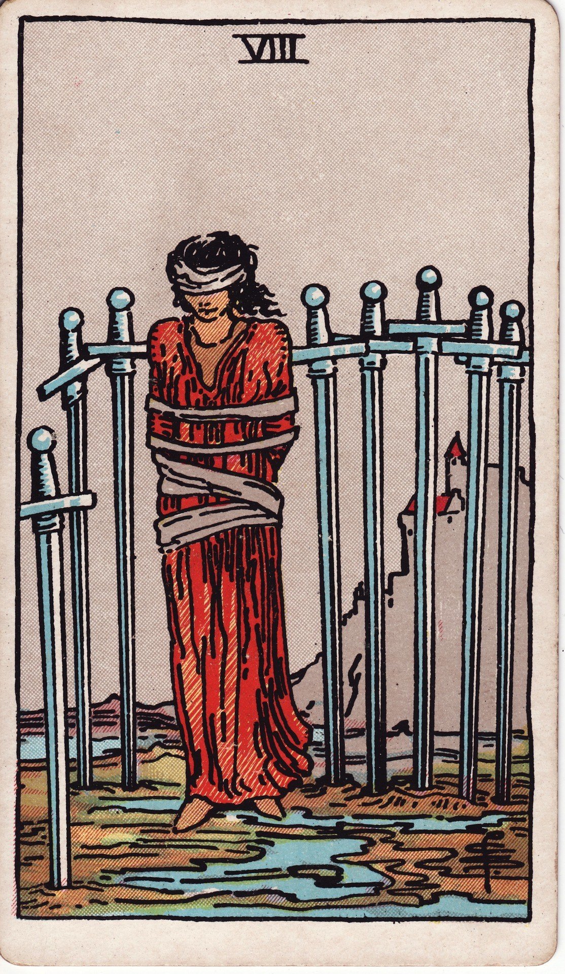 The Eight of Swords from the Rider-Waite-Smith tarot deck: a bound and blindfolded woman stands surrounded by eight swords planted in the ground, a castle visible far behind her on a hill.