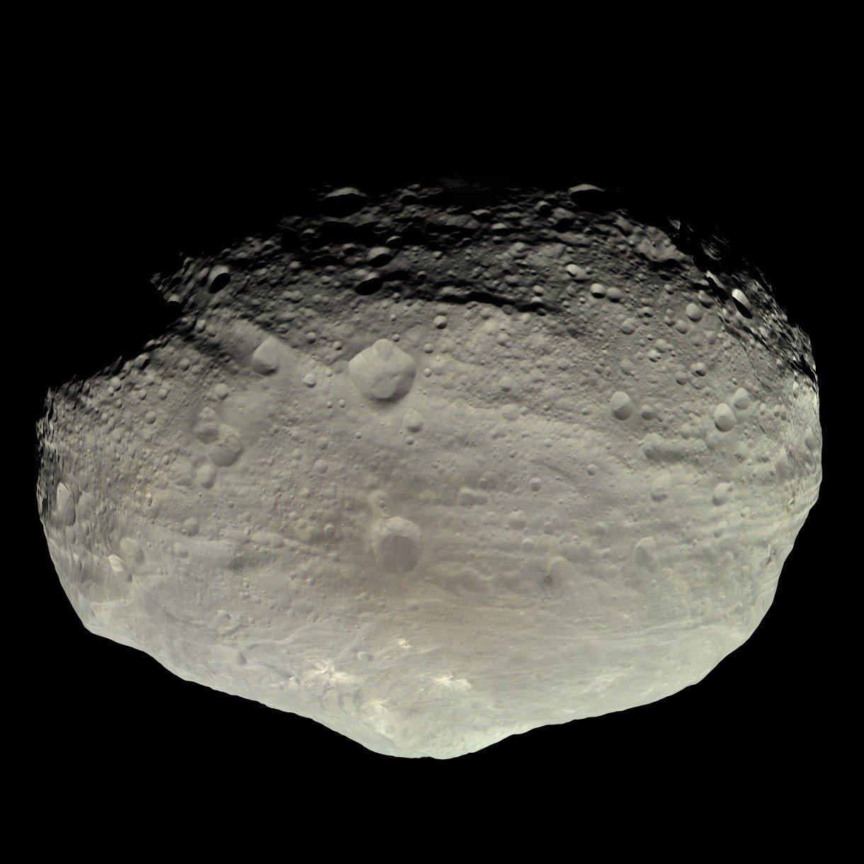 The asteroid Vesta photographed in gray and brown tones, its cratered surface marked by long grooves.