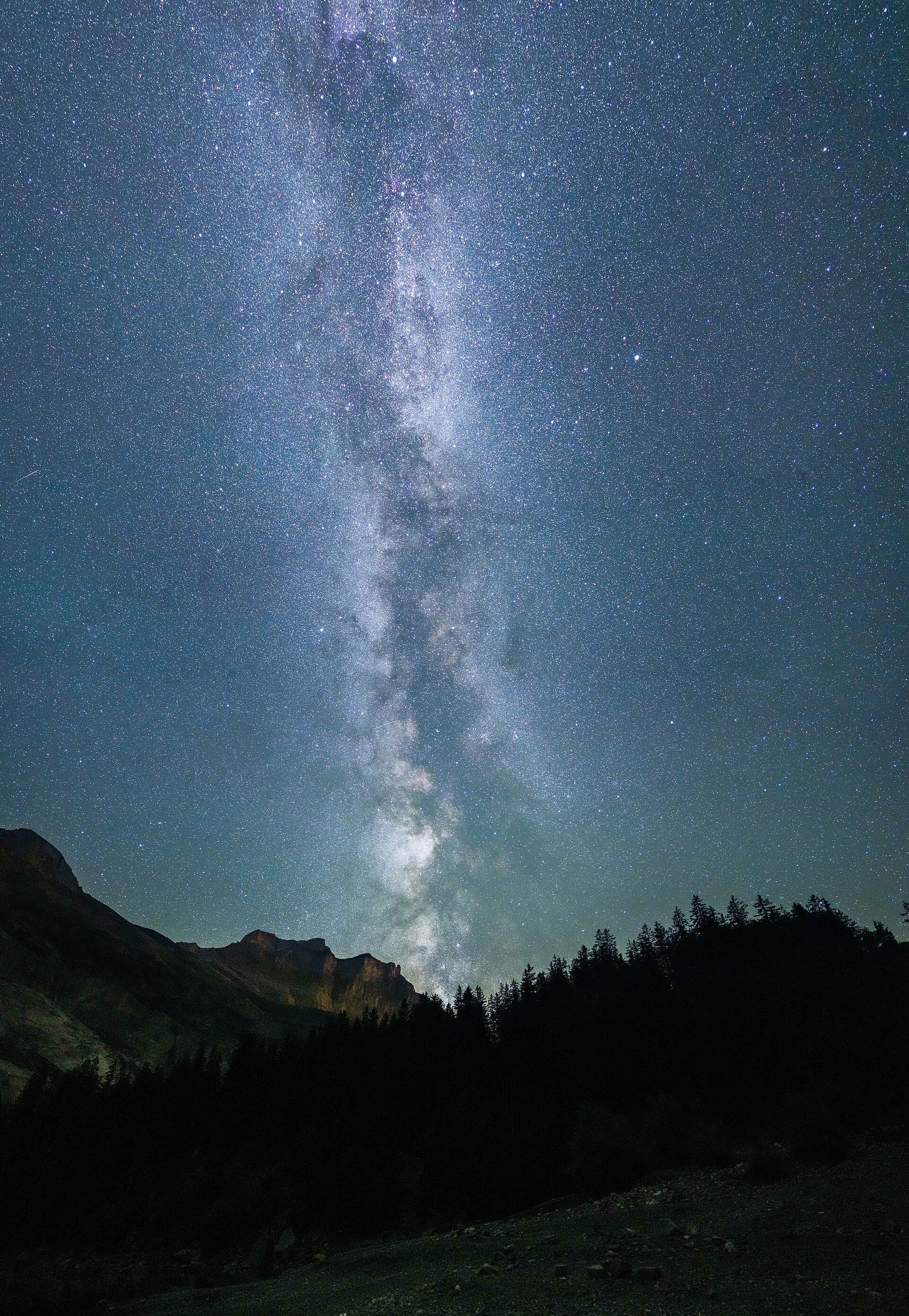 A vertical panorama of the Milky Way over mountain silhouettes