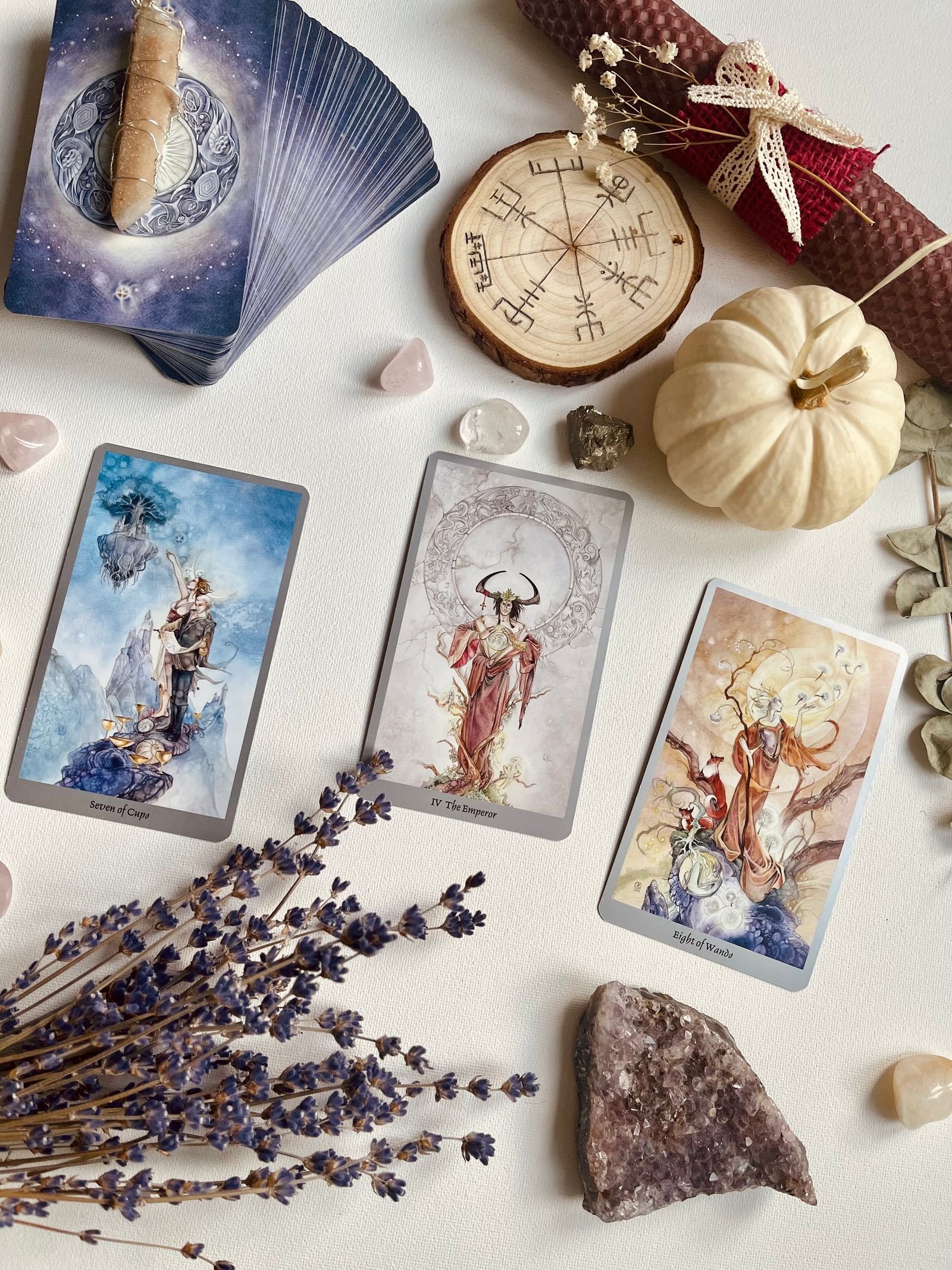 Three tarot cards (Seven of Cups, the Emperor, Eight of Wands) laid out with crystals and lavender