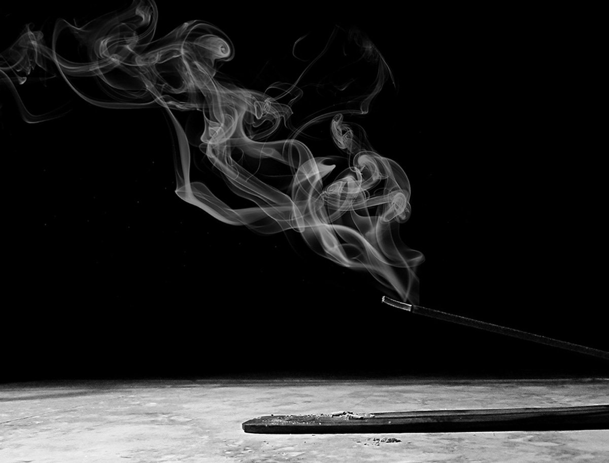 Incense smoke curling upward against a dark background.