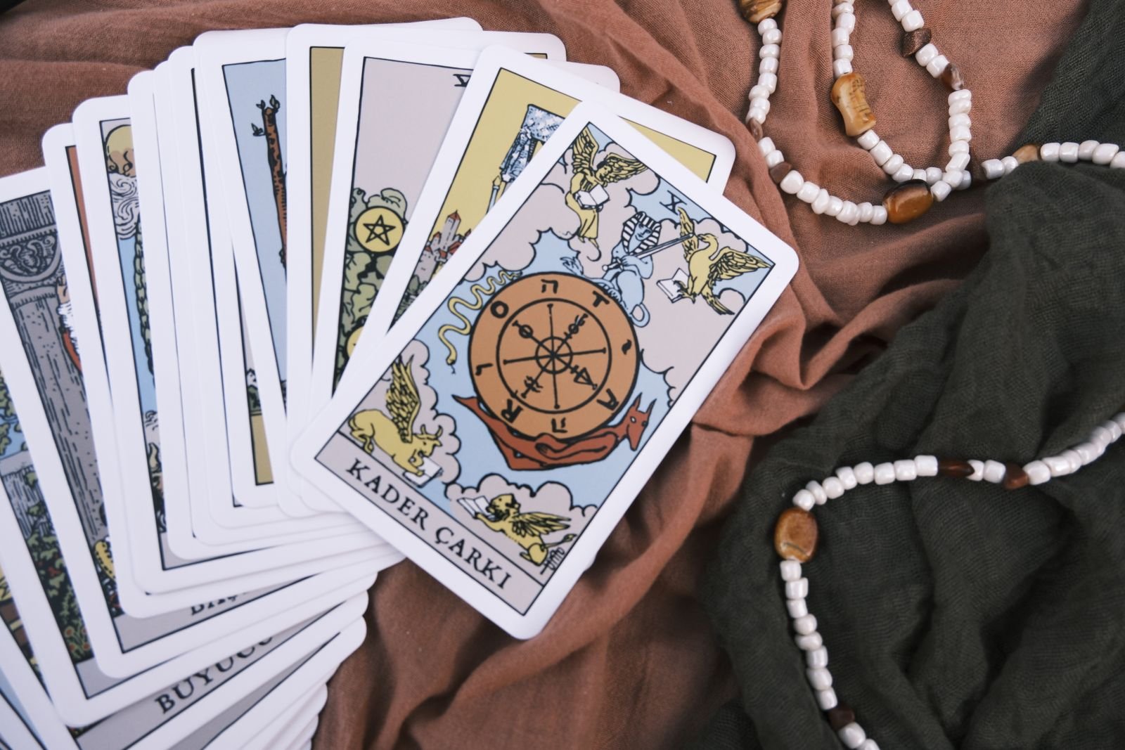 Tarot cards fanned face up, the Wheel of Fortune prominent, with beaded necklaces