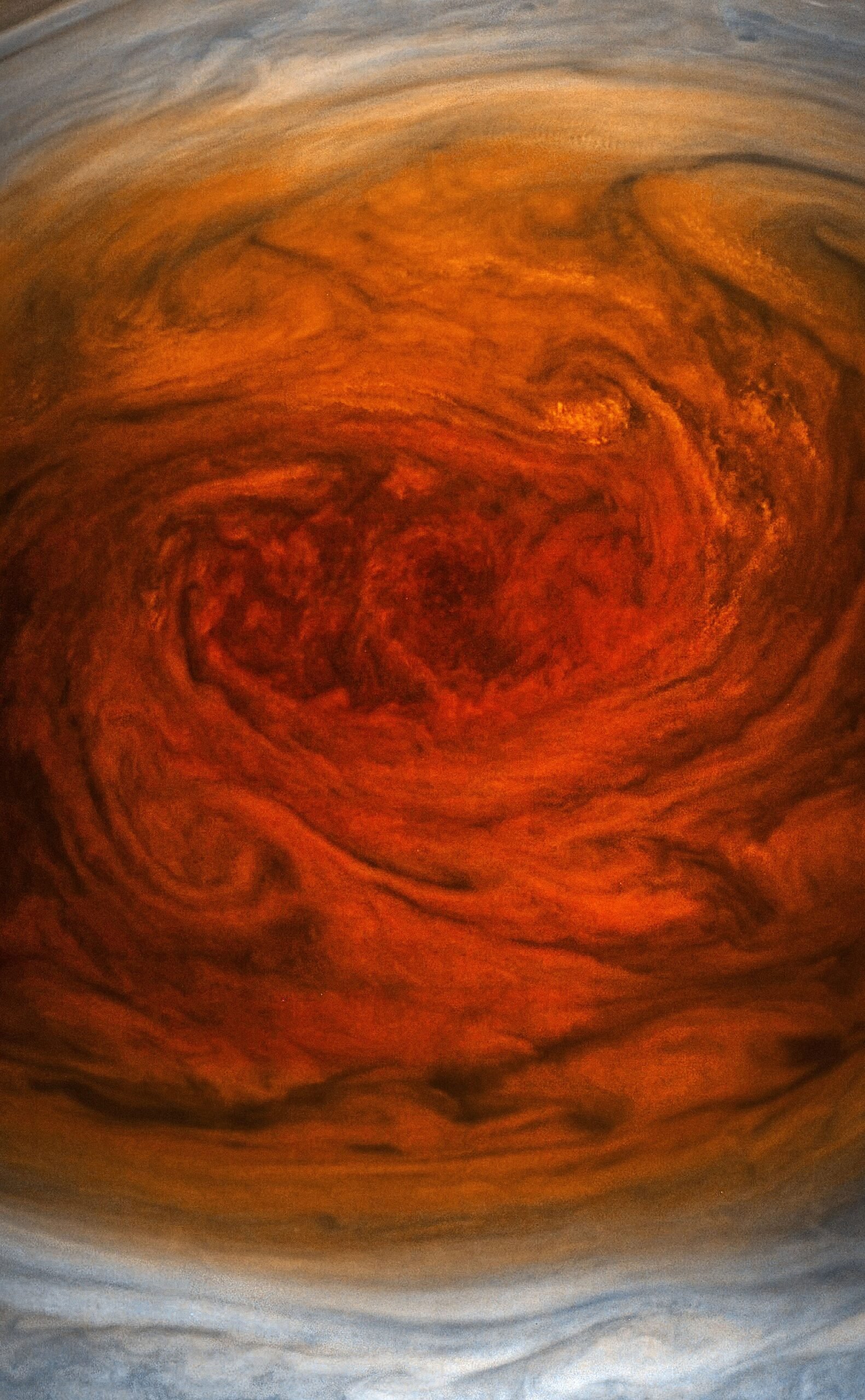 A close-up photograph of Jupiter's Great Red Spot taken by NASA's Juno spacecraft, showing swirling red and orange clouds.