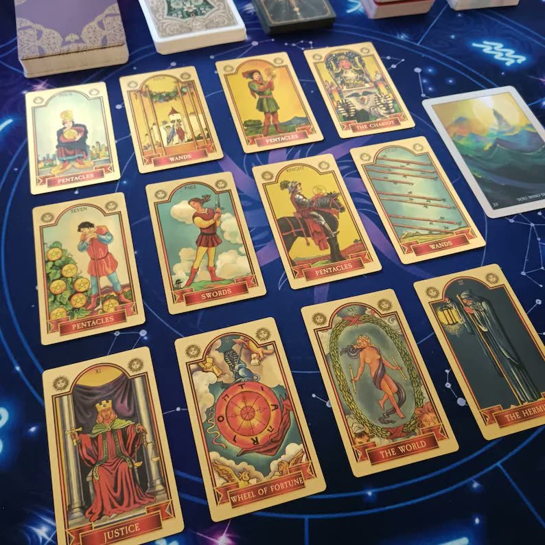 Colorful tarot cards laid out on a blue cloth printed with stars, a phone lying nearby