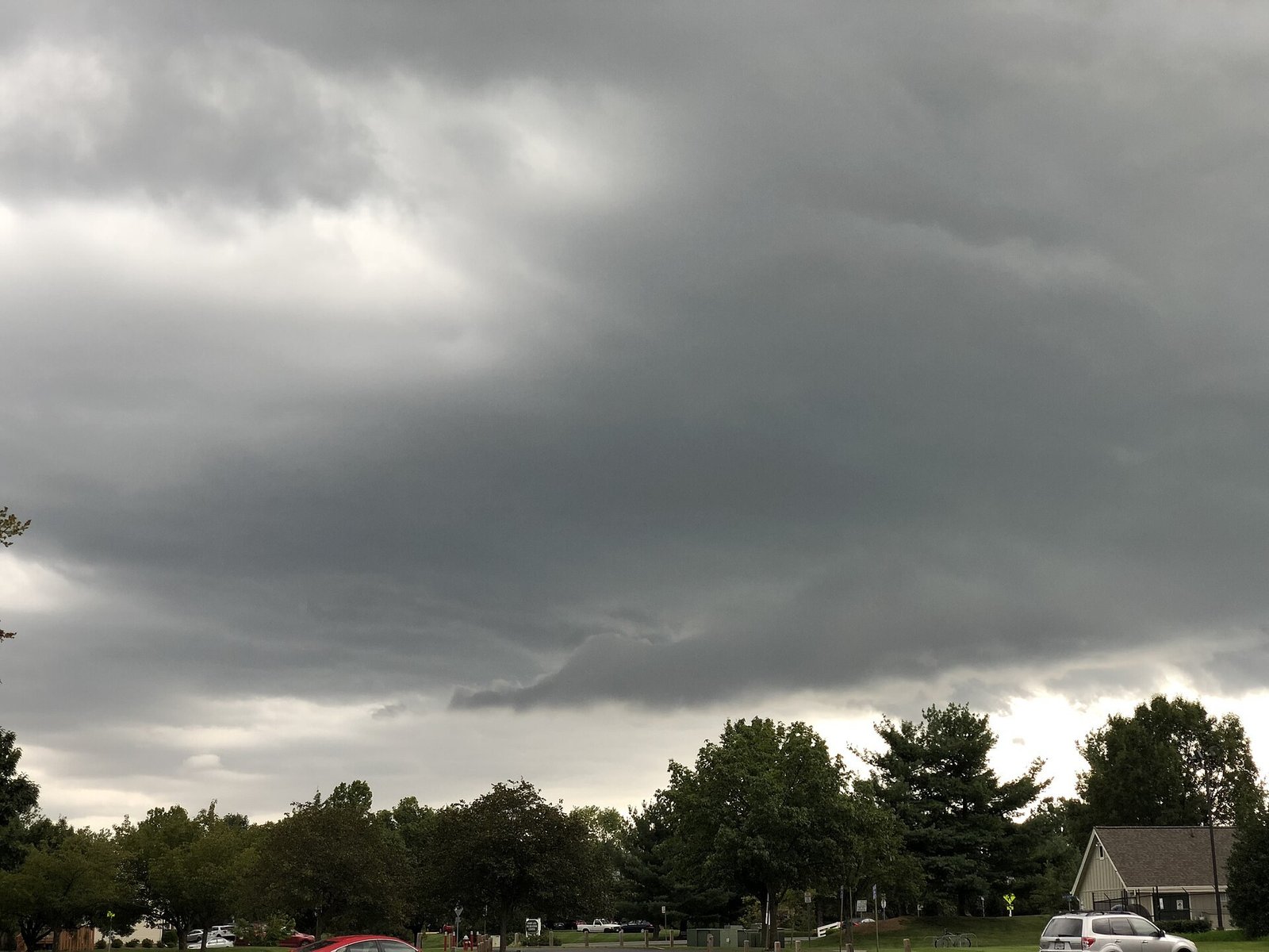 Dark storm clouds gathering over a flat landscape, heavy gray banks of cloud with a thin band of lighter sky at the horizon.