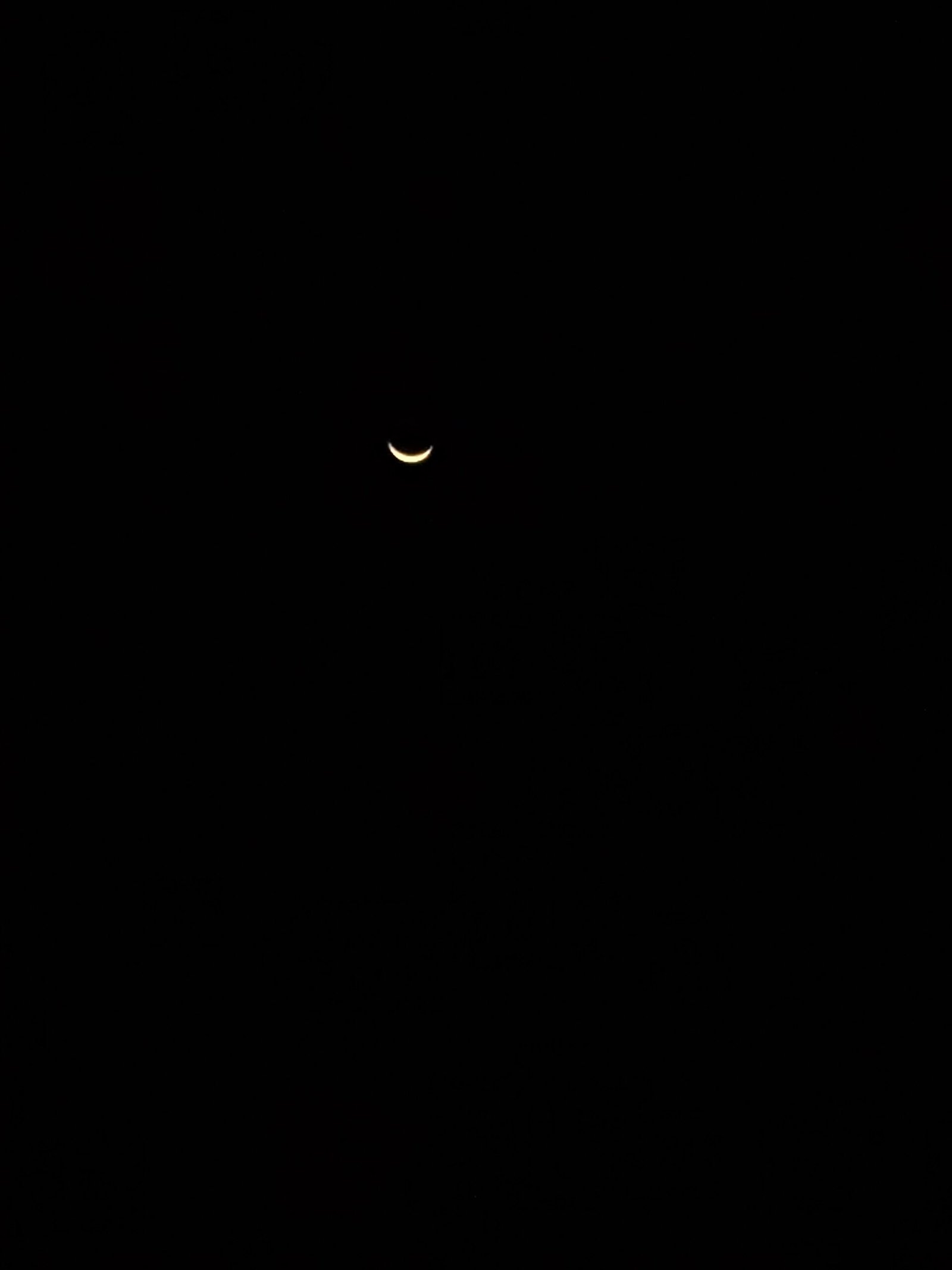 A thin crescent moon in a dark sky