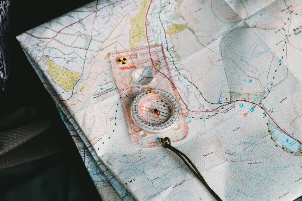 Orienteering compass lying on a folded paper topographic map