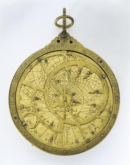 Antique brass astrolabe with engraved rings photographed on a white background