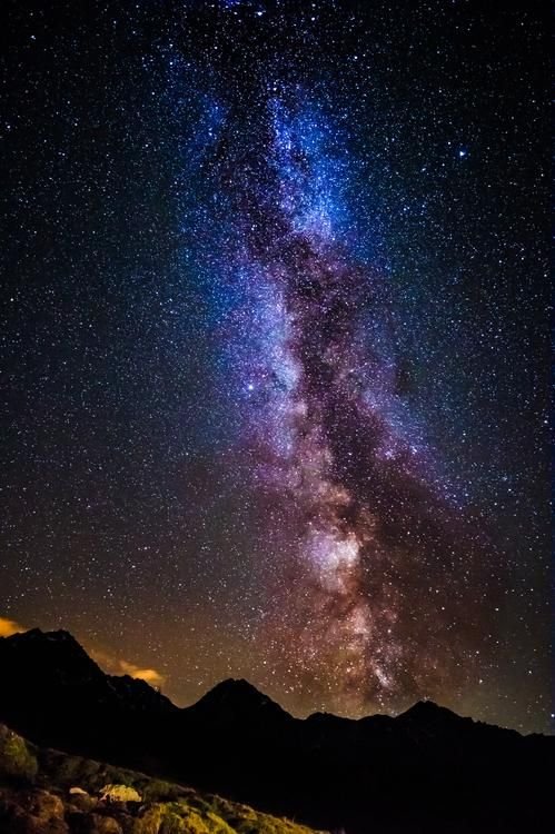 The Milky Way arching over dark mountain silhouettes at night
