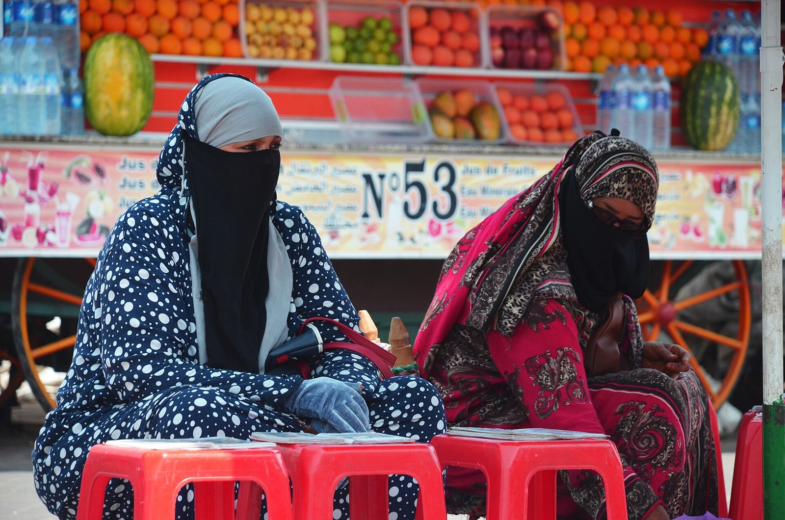 Two tarot readers in veils seated at a market stall in Marrakech