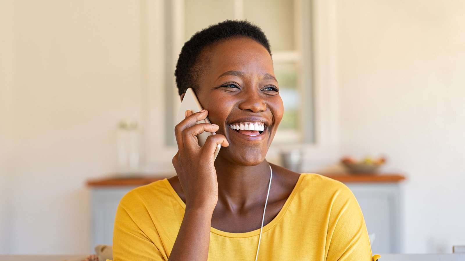 A smiling woman talking on her phone at home