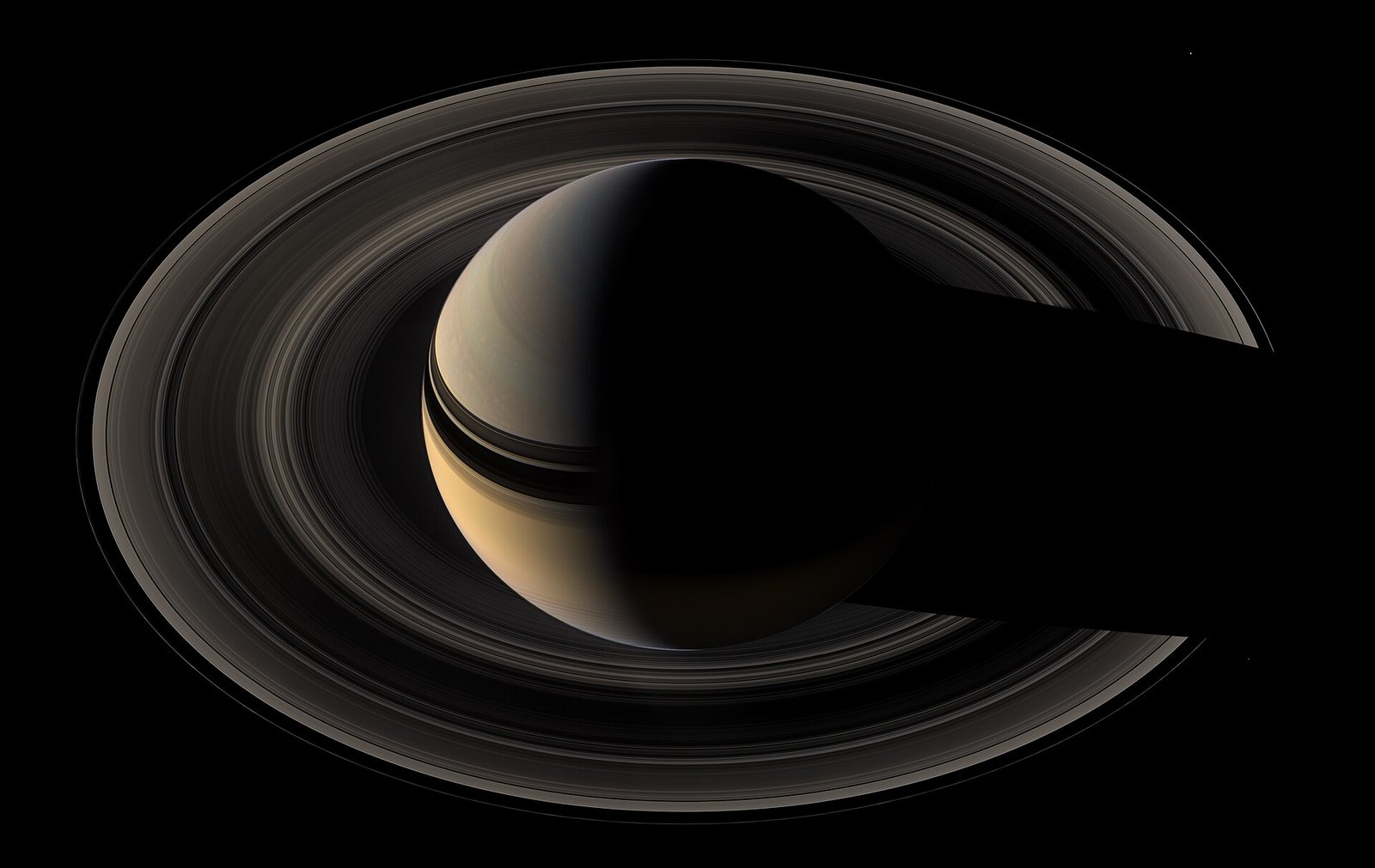 Saturn seen from behind with its rings glowing in backlight, photographed by the Cassini spacecraft in 2007.