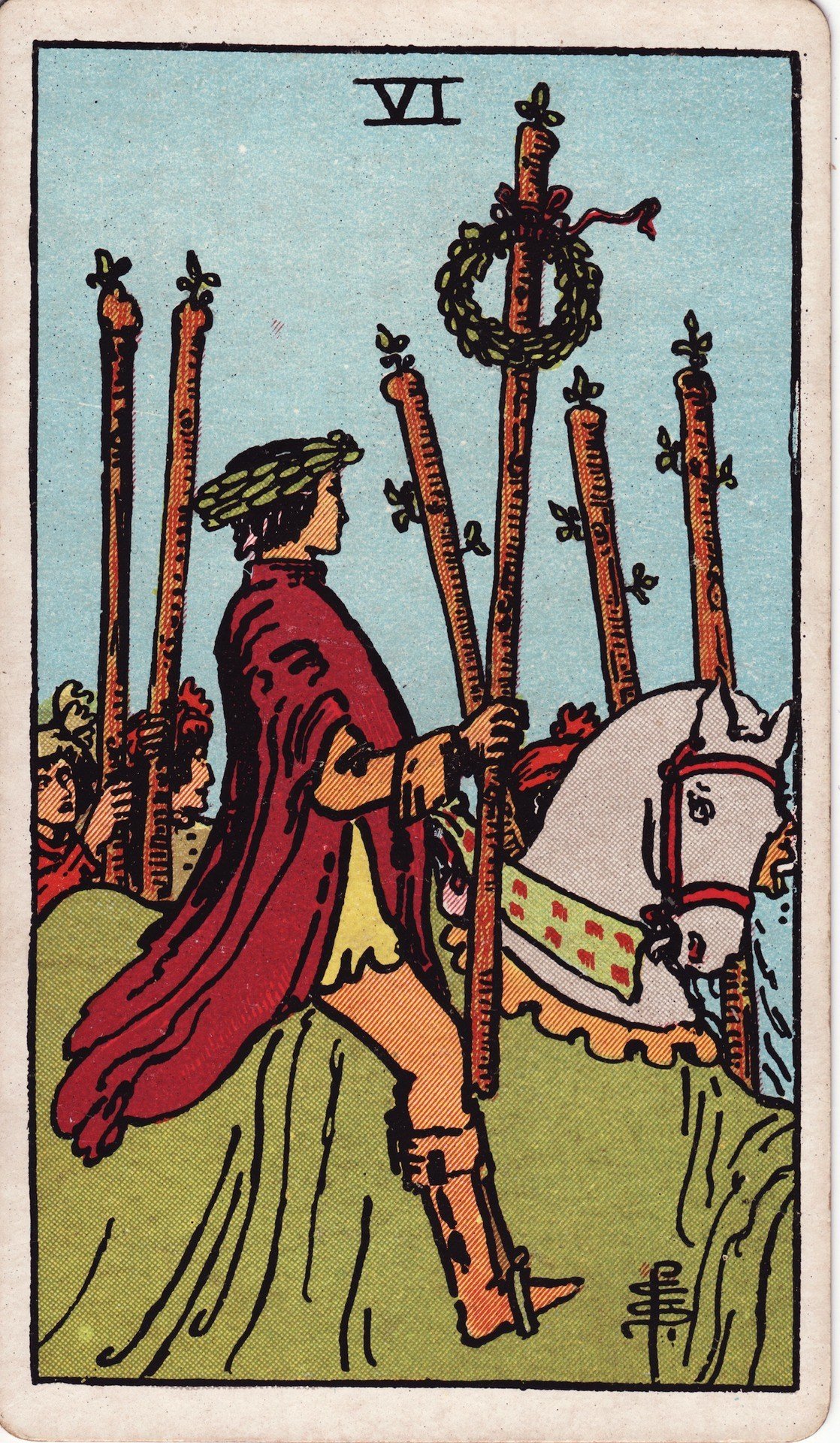The Six of Wands from the Rider-Waite-Smith tarot deck: a laurel-crowned rider on a white horse carries a wand topped with a wreath, a crowd cheering behind him.