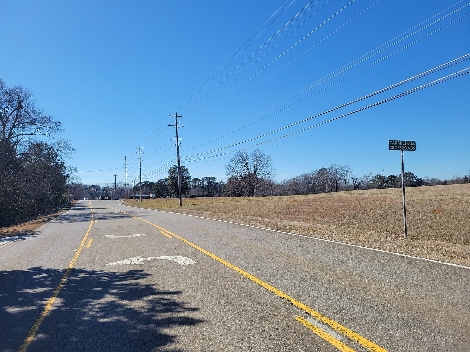 A Carmichael Crossroads sign beside a country road under a clear blue sky