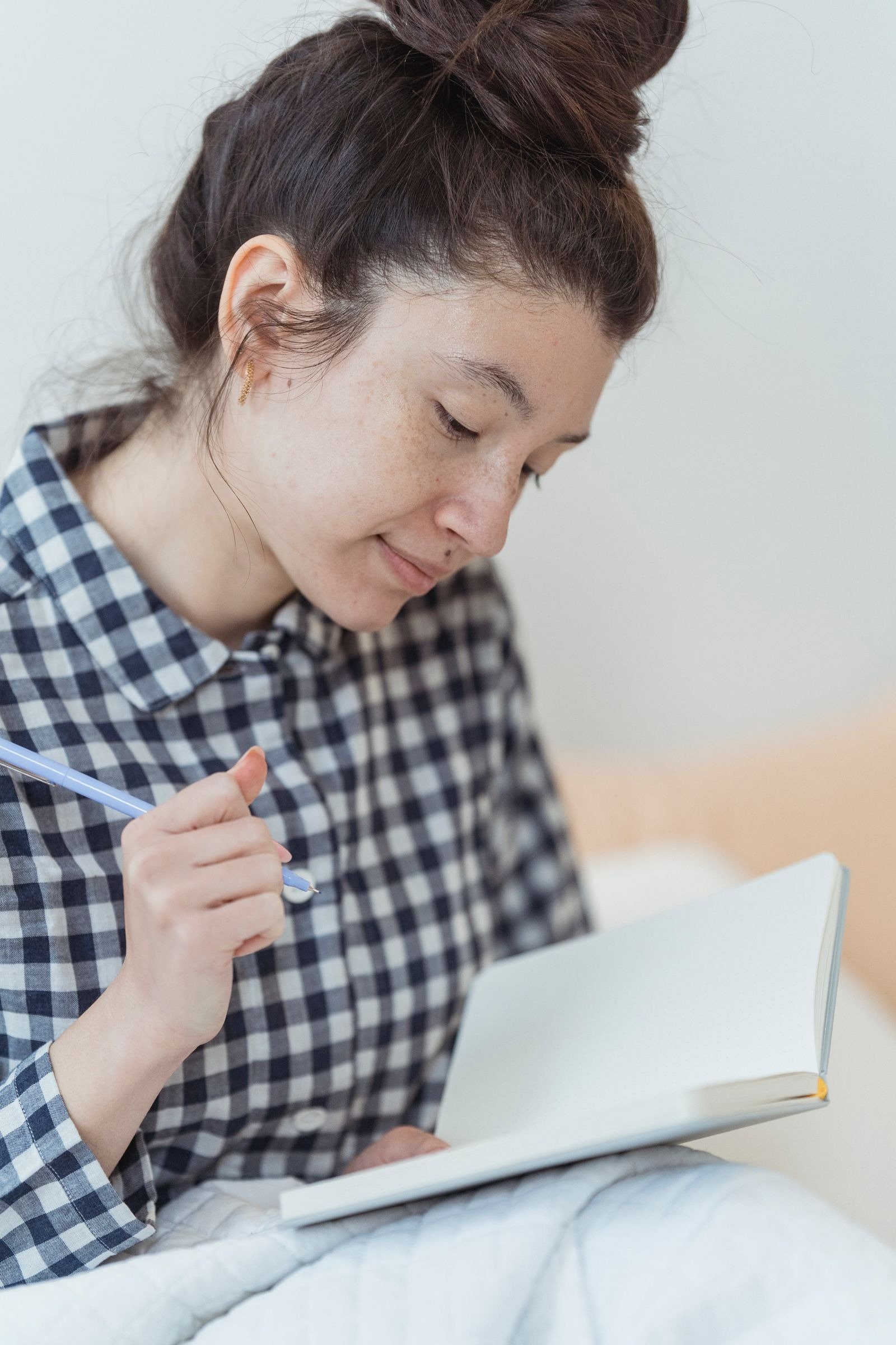 A woman holding a pen over an open notebook.