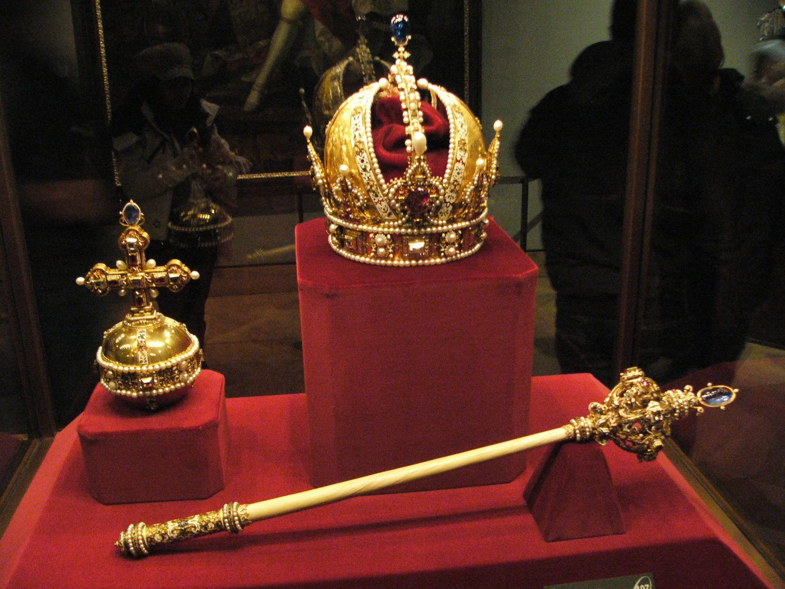 The Imperial Crown of Austria displayed with a golden orb topped by a cross and an ornate scepter on red velvet