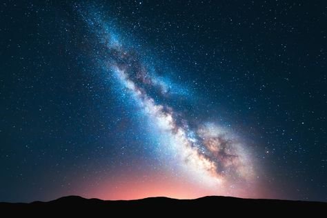 The Milky Way glowing over dark hills under a starry night sky