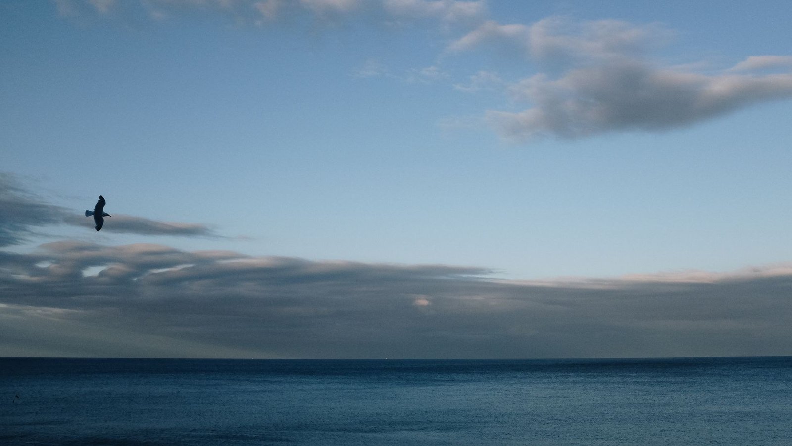 Sunlight breaking through heavy clouds over a calm sea after a storm.