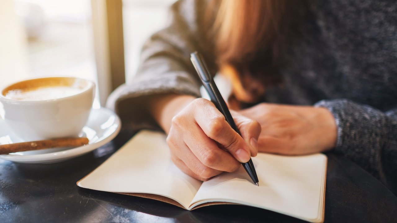 A person writing in a journal during a quiet morning ritual.