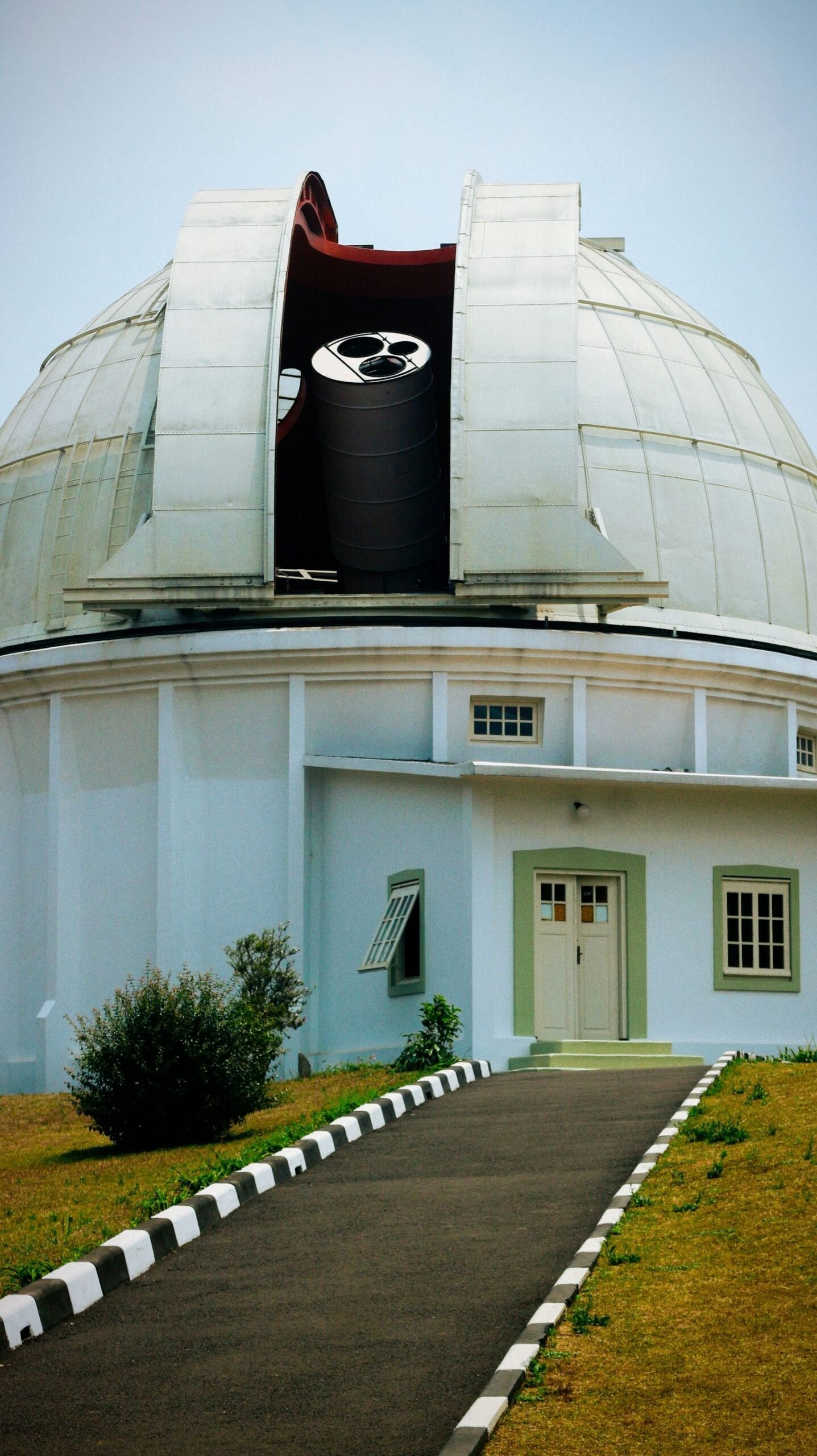 A white observatory building with its dome open, revealing a large telescope inside.