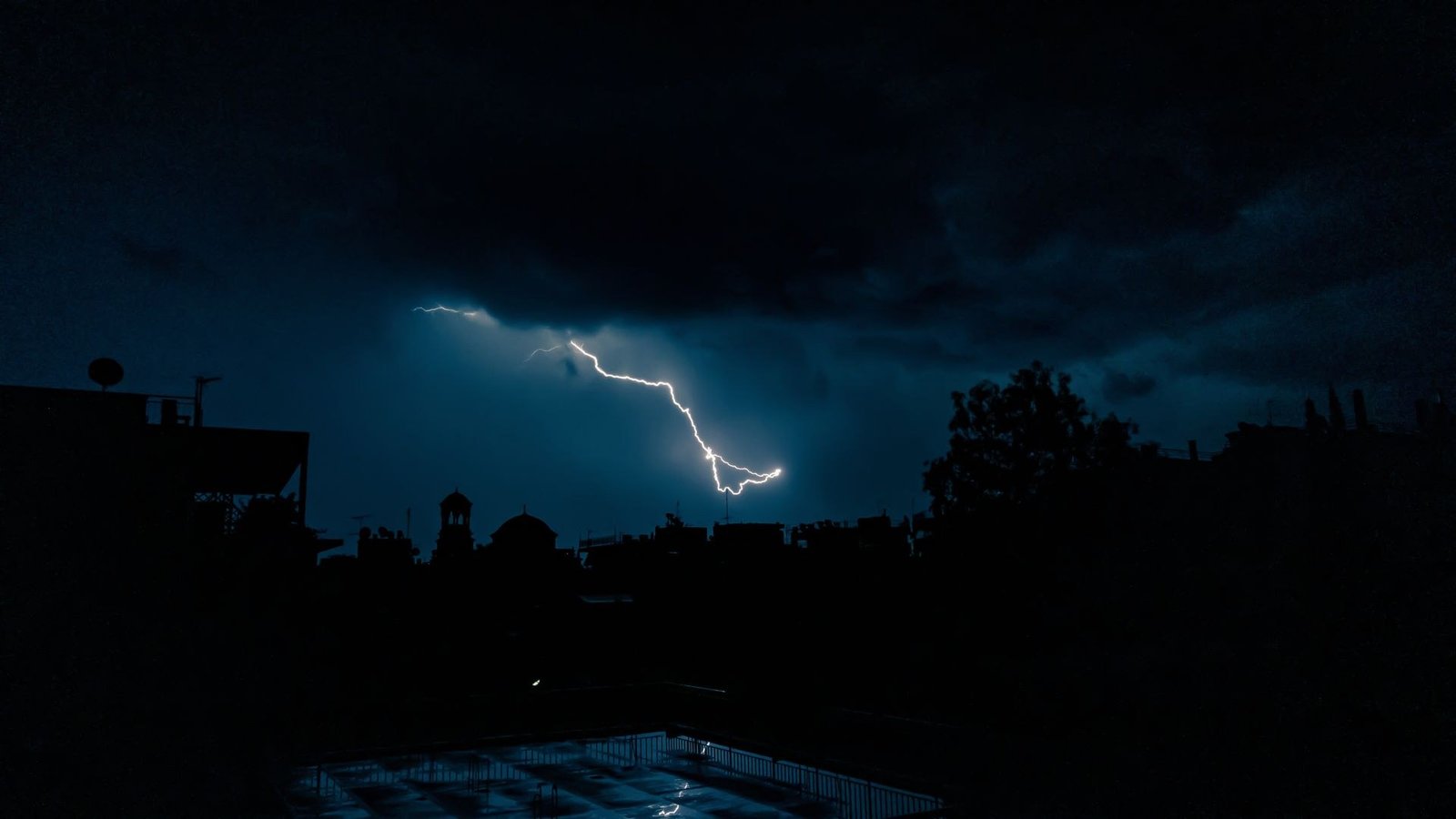 A fork of lightning splitting a dark sky above a flat horizon.