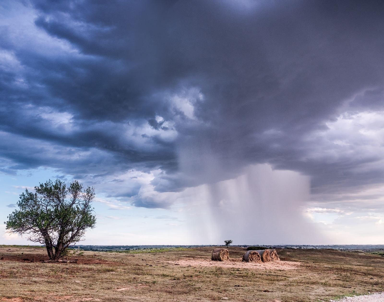 Storm clouds gathering over an open plain, light breaking through in the distance.