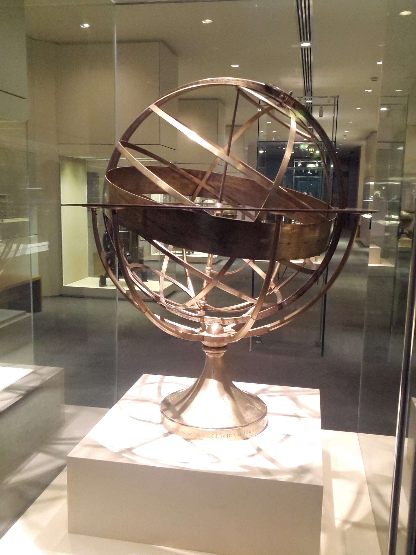 A brass armillary sphere displayed in a museum case.