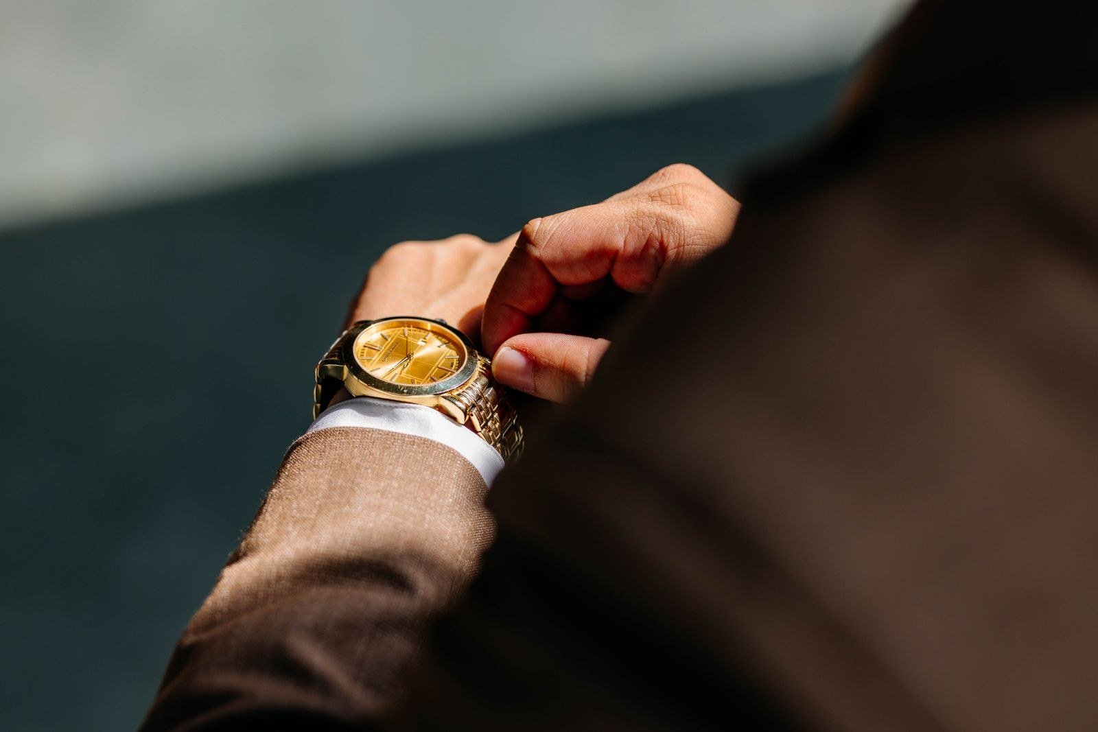 A man adjusting a gold wristwatch on his wrist.